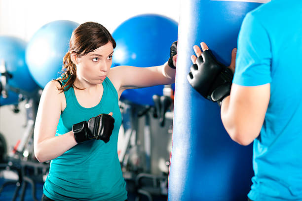istock Female kick boxer with trainer hitting sandbag 119557454