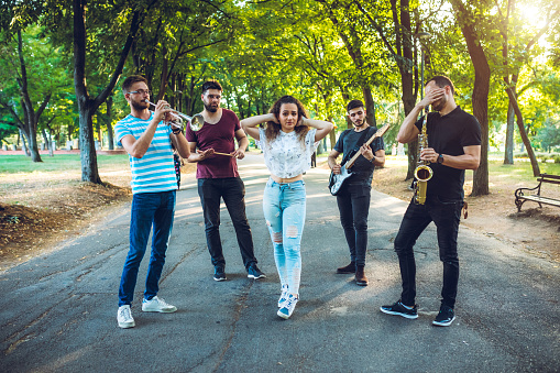 Young band in public park posing with their instruments.
