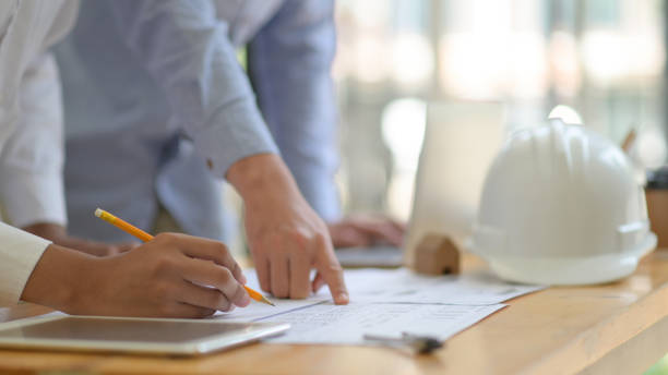 istock The architect is designing the construction. He drafts the floor plan to present to the client. 1195577717