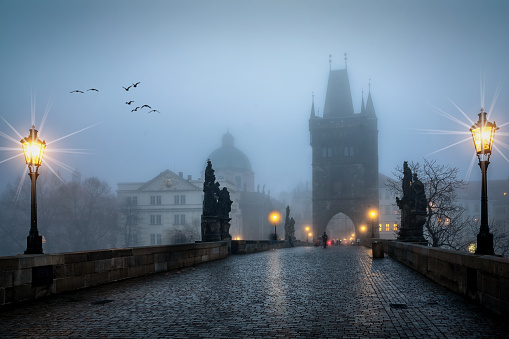 The gothic skyline of Prague, Czech Republic, seen from the famous Charles Bridge on a cold winter morning with fog