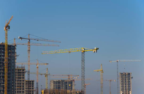 istock Tower cranes constructing a new residential building at a construction site against blue sky. Renovation program, development, concept of the buildings industry. 1195581573