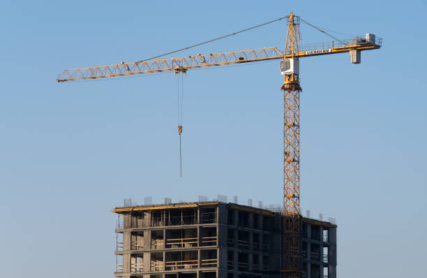 istock Liebherr tower crane constructing a new residential building at a construction site against blue sky. 1195583460
