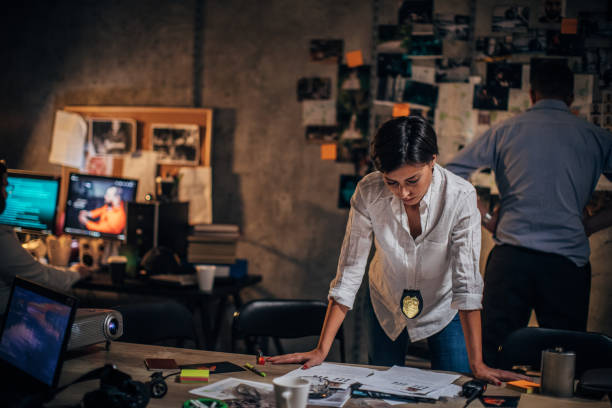 istock Lady detective working late with colleagues in office 1195584876