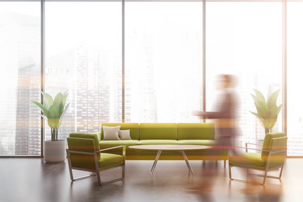 istock Man walking in panoramic lounge with green sofa 1195585095