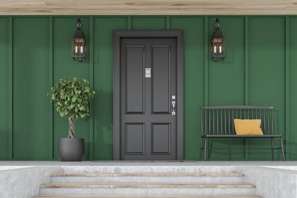 istock Black front door of green house, tree and bench 1195585164