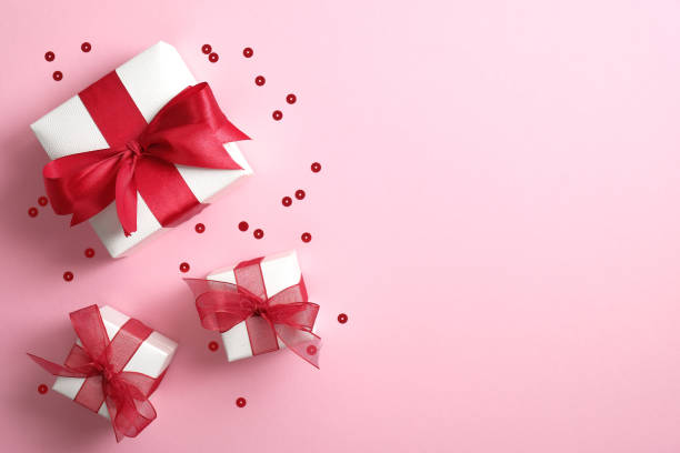 istock White gift boxes with red ribbon bow on pink background with confetti. Saint Valentine's Day surprise, love concept. Flat lay, top view. 1195585735
