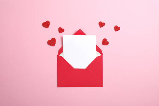 内側に白いノートモックアップが入った赤い紙の封筒と、ピンクの背景にバレンタインハート。フラットレイ、トップビュー。バレンタインデーのコンセプトのためのロマンチックなラブレ� - ロマンス 写真 ストックフォトと画像