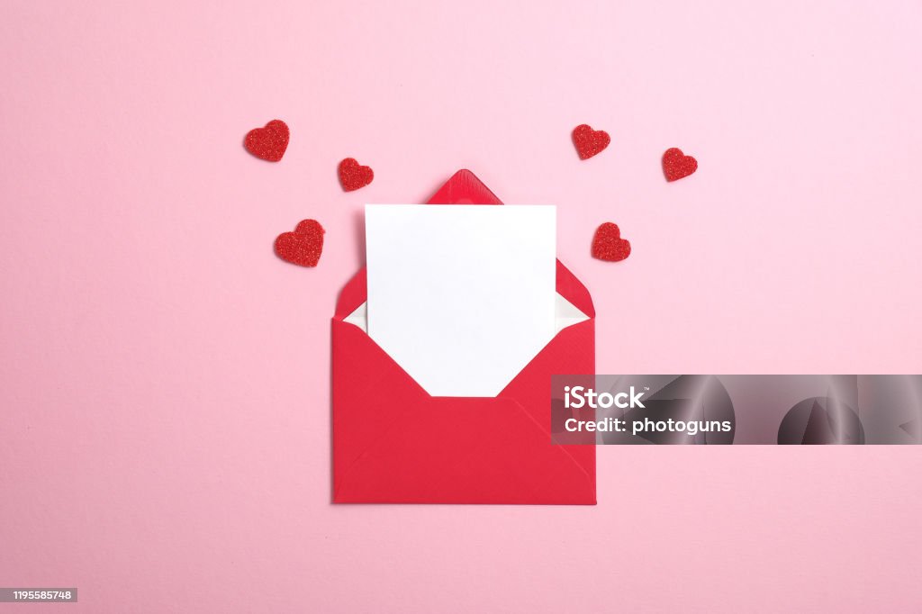 Red paper envelope with blank white note mockup inside and Valentines hearts on pink background. Flat lay, top view. Romantic love letter for Valentine's day concept. Valentine's Day - Holiday Stock Photo