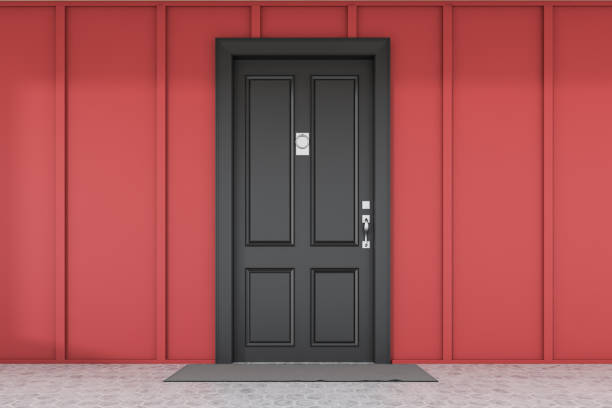 istock Black front door of red house with mat 1195586205