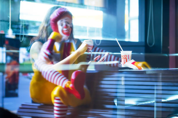 A Ronald McDonald statue and an Asian woman reflection on the mirror. Bangkok, Thailand - JULY 9, 2019: A Ronald McDonald statue and an Asian woman reflection on the mirror of the McDonald's fast-food restaurant. Wang Thonglang. smart phone technology lifestyles chain stock pictures, royalty-free photos & images