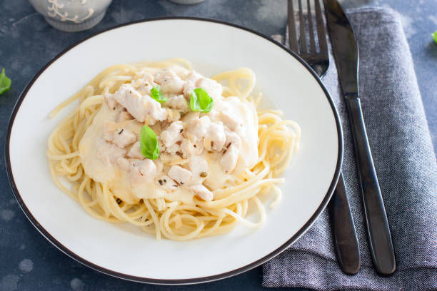 istock Spaghetti with chicken and cheese sauce on a white plate, horizontal 1195595560
