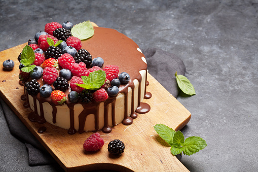 Chocolate cake or cheesecake with berries. On wooden board with copy space