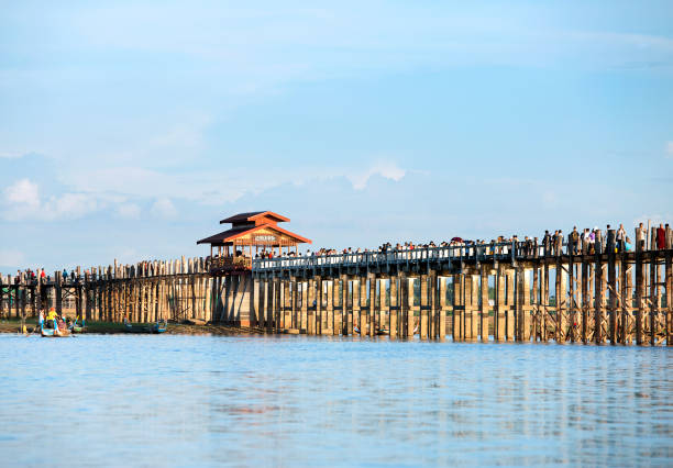 U Bein Bridge, Mandalay, Myanmar. U Bein Bridge is the oldest and longest span teakwood bridge in the world crossing the Taungthaman Lake near Amarapura, Myanmar, a tourist attraction that generates income for row boat owners as well as local fishermen and farmers.