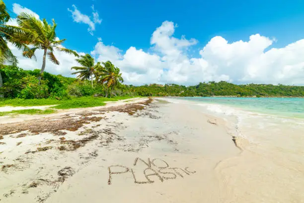 No Plastic written on white sand  in a beautiful tropical beach in the Caribbean sea