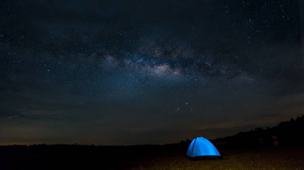 Camping under the stars. The Milky Way stretches overhead a blue  tent high In the pasture stock photo