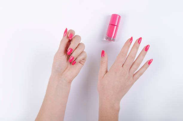 woman's hand with pink nail polish on white background
