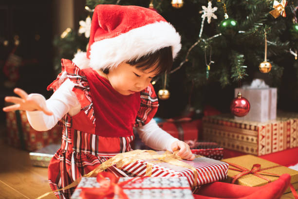 istock Girl Opening Gift While Siting By Christmas Tree 1195600839