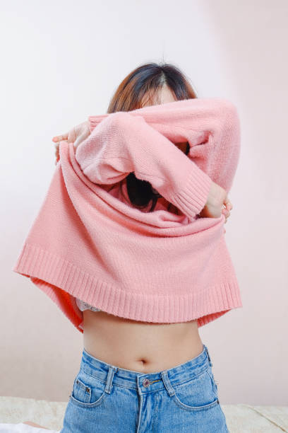 十代の少女は自宅でセーターを取り外しています。 - undressing ストックフォトと画像