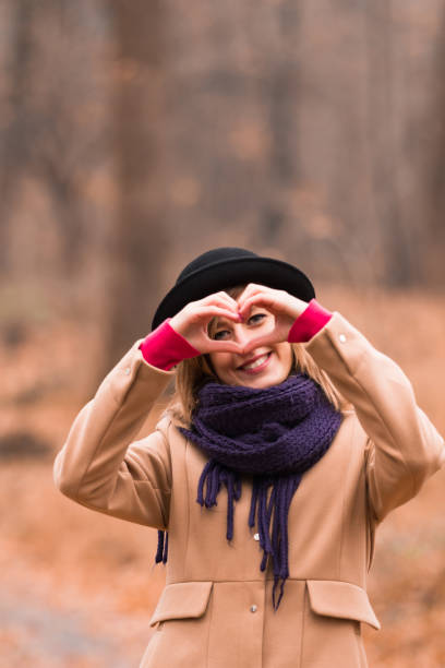 joven mujer al aire libre haciendo corazón - símbolo de forma para el amor y el romance. - heart shape loneliness women praying fotografías e imágenes de stock