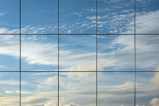 Sky reflection in modern skyscraper window. Cloudscape view reflected in futuristic architectural structure. Abstract view, space for text