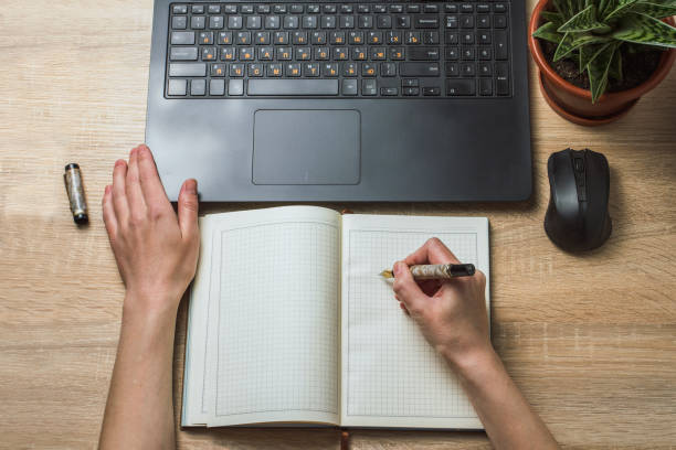 istock Female hands Notebook Diary and Wireless Mouse. Office space and working atmosphere. Top view 1195604103