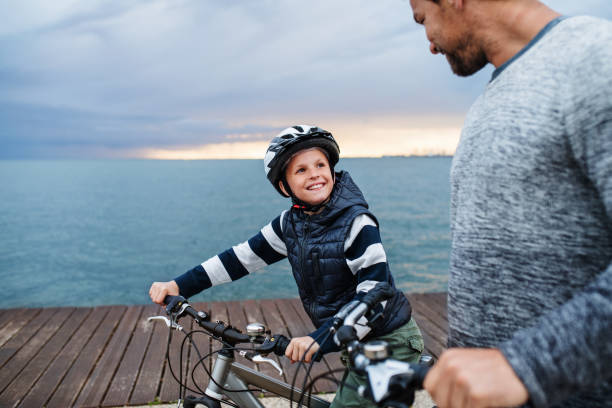 istock Father and small son with bicycles outdoors standing on beach. 1195604957