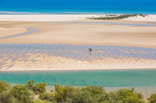 Lowtide aerial view of tourists walking across a sand bar at the Ria Formosa in Portugal.