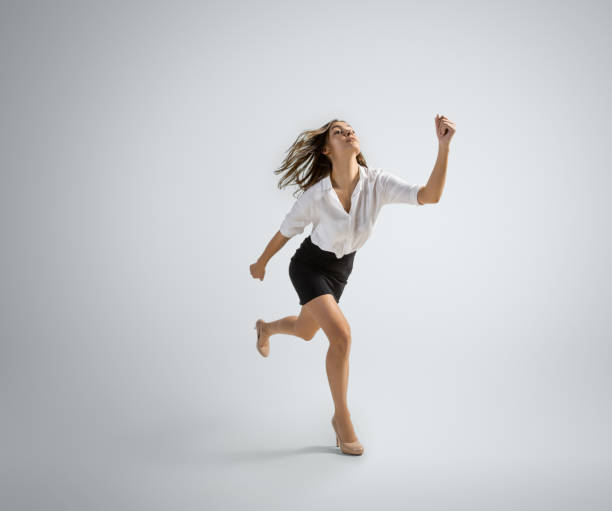 istock Caucasian woman in office clothes running isolated on grey studio background 1195606529