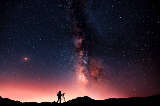 beautiful starry night landscape. a silhouette of a photographer stands on a hill and looks at a beautiful starry sky with a bright milky way - nature photographer imagens e fotografias de stock