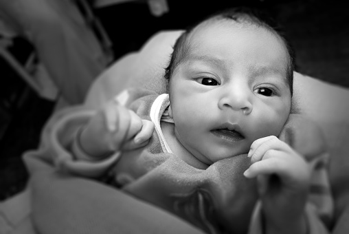 Innocent newborn baby girl looking at camera, close up portrait.