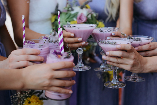 bride and bridesmaids celebrate wedding with purple cocktail