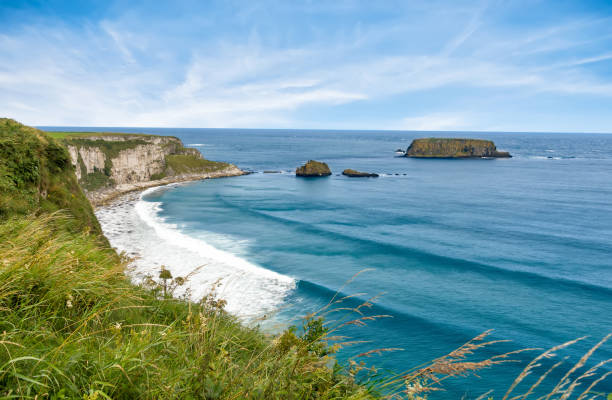 costa del norte de irlanda en carrick-a-rede en ballycastle. paisaje escénico de laderas de hierba, acantilados de roca y todavía olas desde el mar de irlanda extendiendo la costa. - carrick a rede fotografías e imágenes de stock