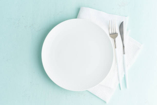 istock Clean empty white plate, fork and knife on green blue turquoise stone table, copy space, mock up 1195615191