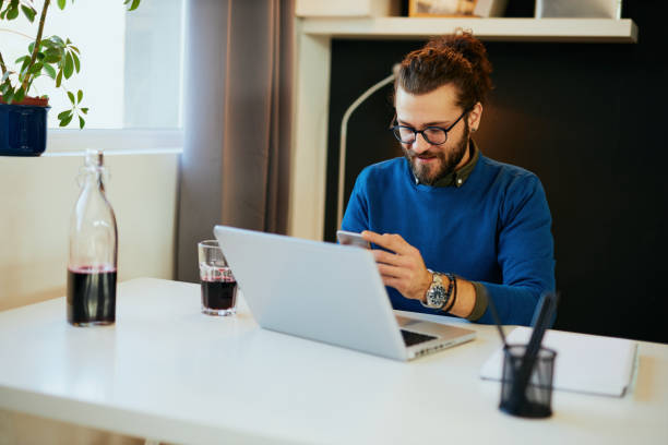 istock Attractive caucasian bearded entrepreneur sitting in his office, using smart phone and taking a break from work. 1195618991