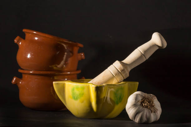 clay bowls next to a syrup and two garlic heads, all over black