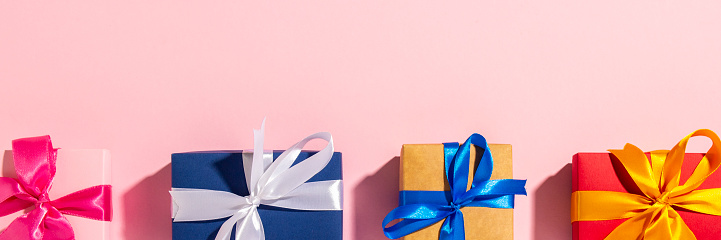 Gifts with a ribbon on a pink background under natural light. Modern. Concept holiday, family, beloved, for him. Banner. Flat lay, top view.