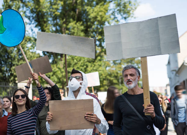istock People with placards and protective suit on global strike for climate change. 1195621814