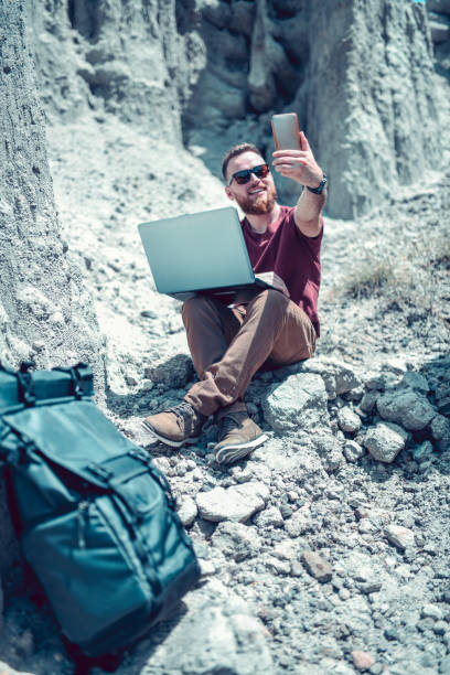 istock Male Explorer Taking Notes And Selfie While Traveling Rocky Lands 1195623839