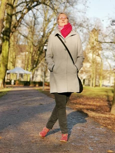 istock Young woman enjoying the warm winter sun while taking a stroll through a park 1195624819
