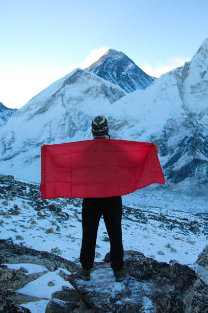 o homem prende a bandeira vermelha com espaço da cópia para sua decoração na frente da montanha borrada de everest. vista para trás. - kala pattar - fotografias e filmes do acervo