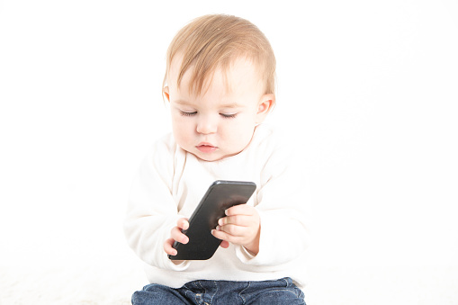 Stock studio photo with a white background of a baby with a mobile in his hand