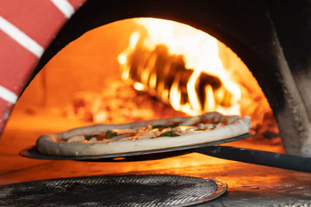 istock Pizza is shoved into a wood-burning oven for baking on a shovel. 1195628264