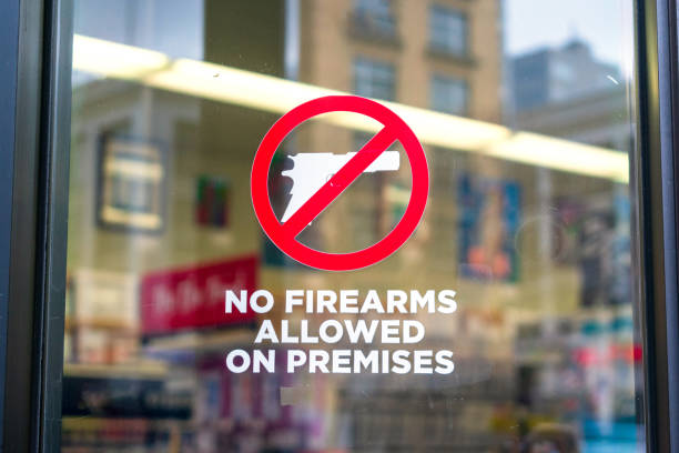 No firearms allowed on premises sign on the glass entrance door to establishment notifies patrons that weapons aren't allowed. No firearms allowed on premises sign on the glass entrance door to establishment notifies patrons that weapons aren't allowed, addresses security policy and protection concerns. gun control photos stock pictures, royalty-free photos & images