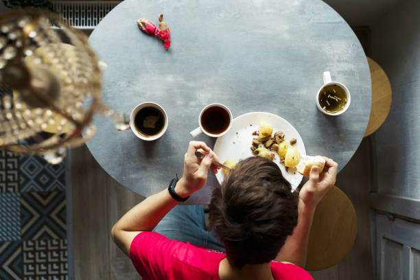 istock Breakfast at the oval table by the window. Boy eating potatoes and drinking coffee from white ceramic mugs 1195633777
