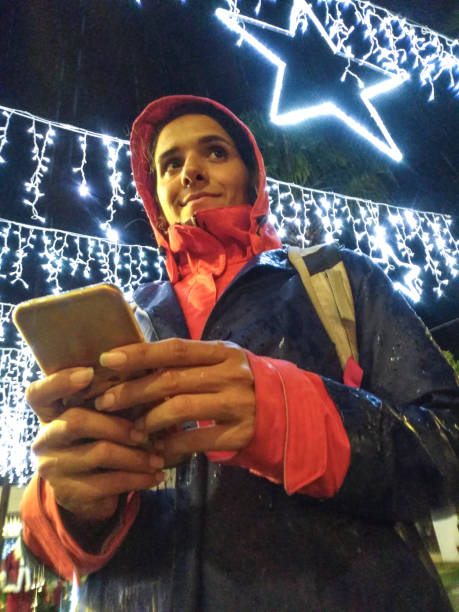 istock Girl With Her Phone Under Christmas Lights 1195638746