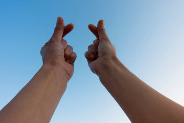 Close-up of cropped hand gesturing finger heart sign against the clear sky.