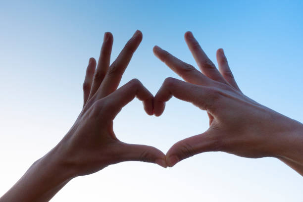 istock Cropped hand gesturing heart shape, sign against the clear sky. 1195639067