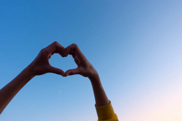 istock Cropped hand gesturing heart shape, sign against the clear sky. 1195639074