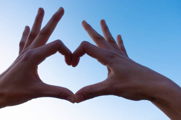 istock Cropped hand gesturing heart shape, sign against the clear sky. 1195639137