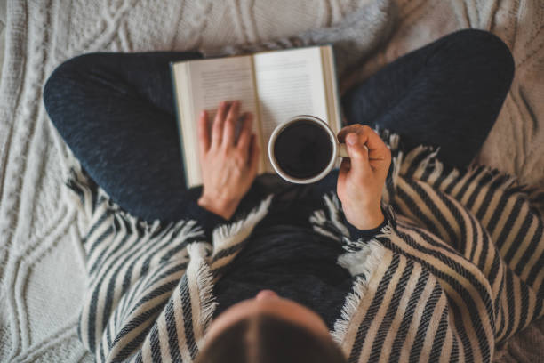 istock Woman drinking coffee at home on a sofa reading a book 1195640203